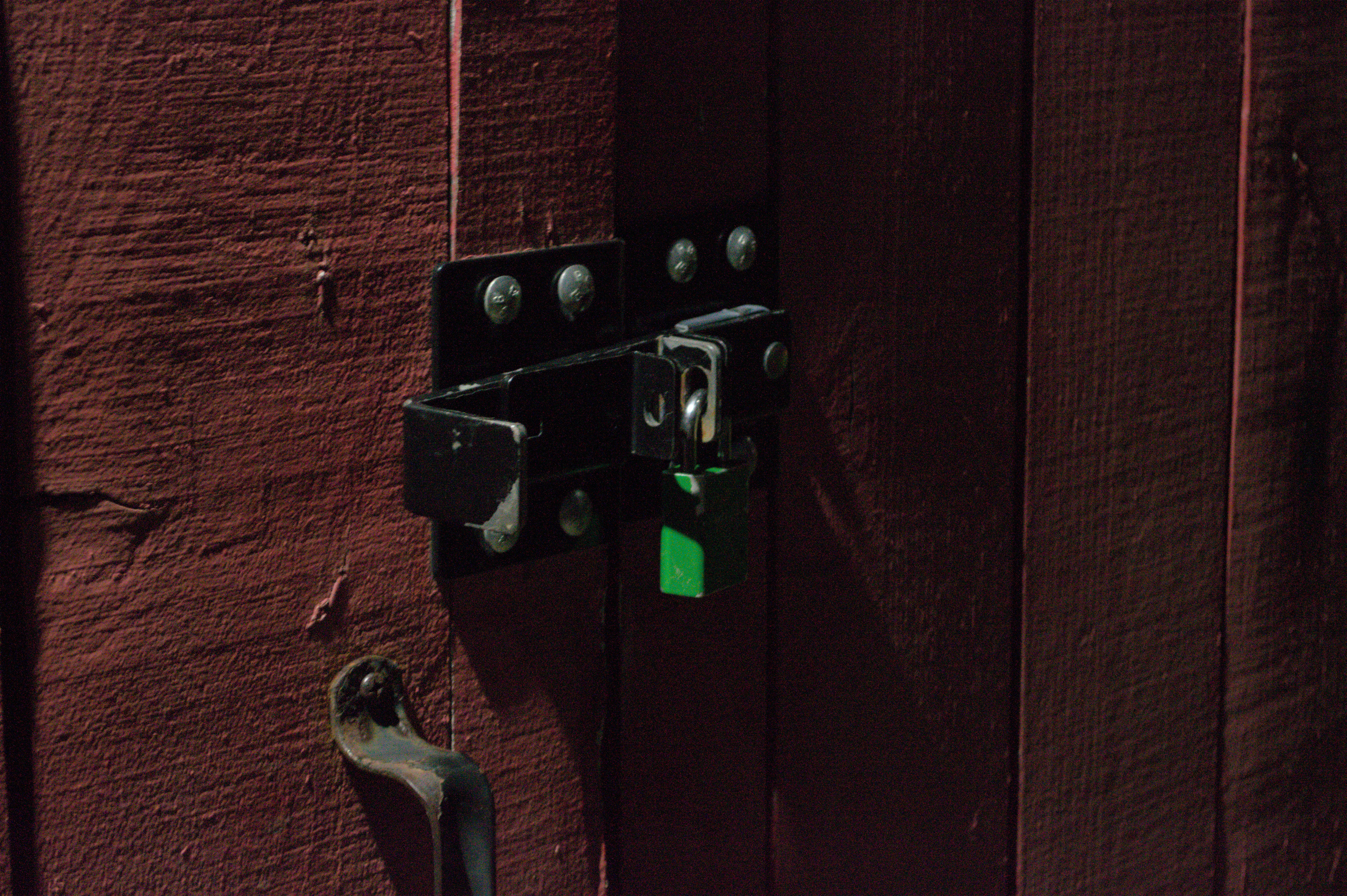 Photo of a padlock on a red barn door, light by a small light
